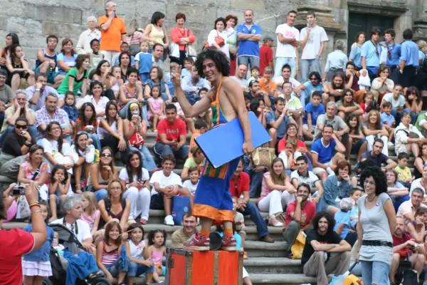 Artista de circo Pablo Trasno realizando una acrobacia o malabarismo en un espectáculo de calle, con público observando.